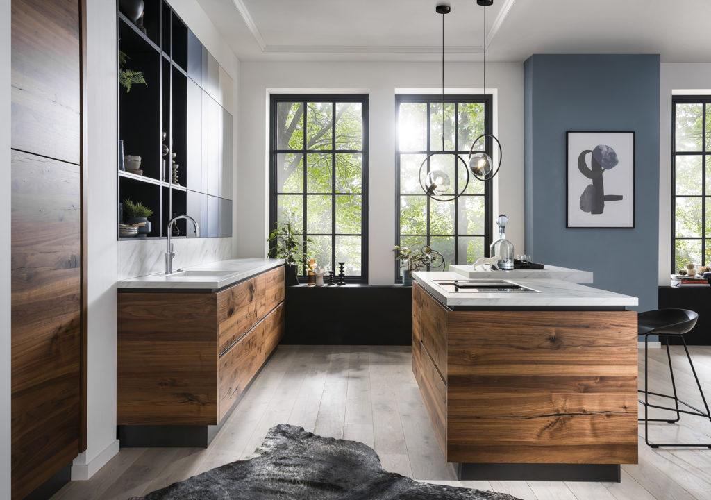 Preciosa cocina con ventanales y vistas al bosque. Cocina con muebles en acabado madera natural y toques en azul.