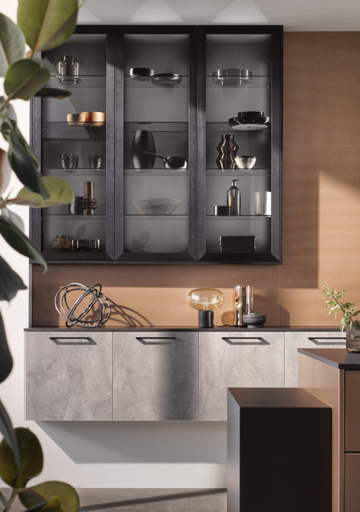 Cocina moderna con muebles en textura piedra y dorado. Cocina con vitrina oscura.