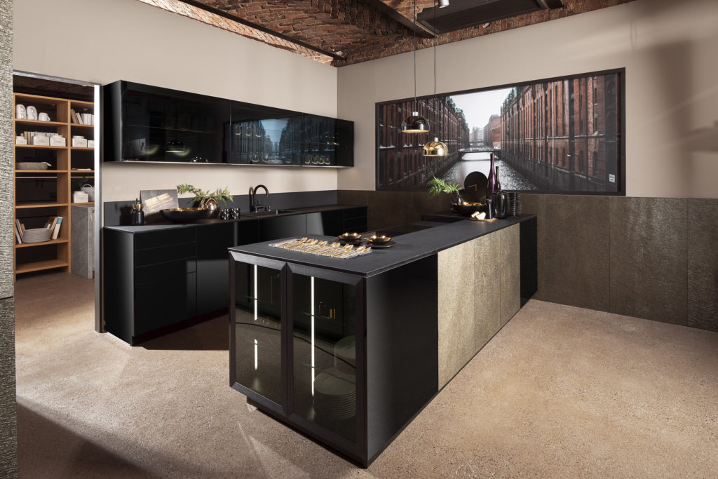 Cocina moderna de acabado negro brillante con vitrinas y toques dorados. Cocina con isla.