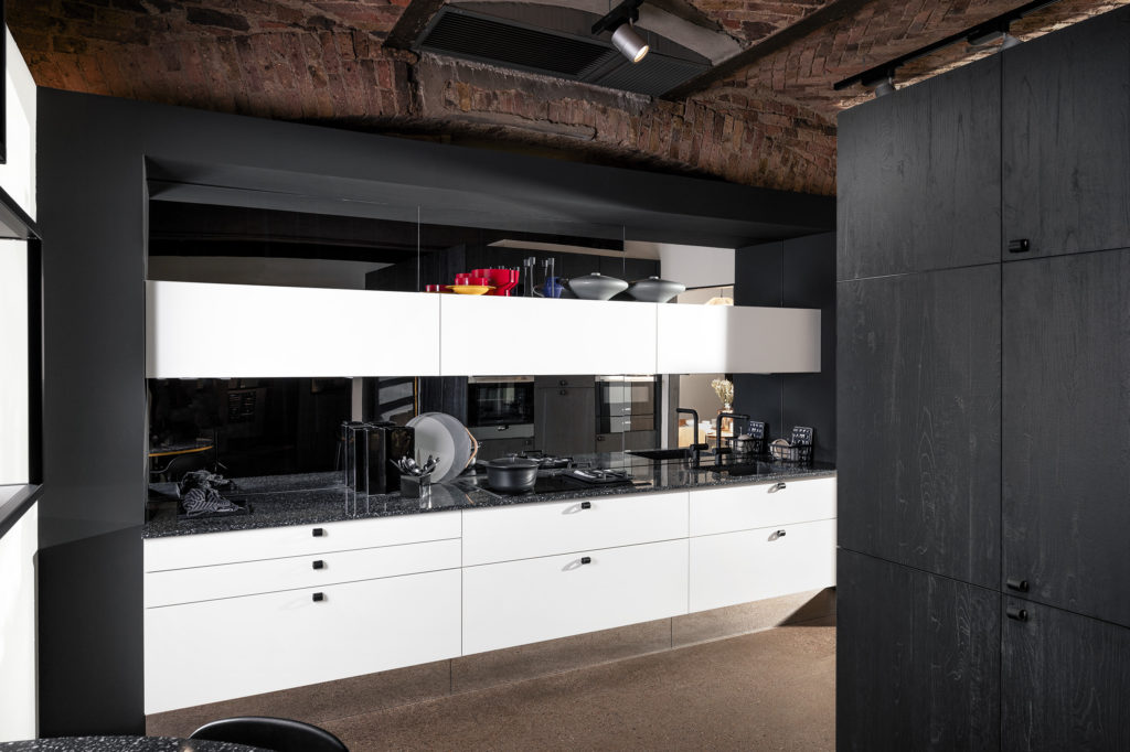 Cocina con mueble blanco y tirador de pomo con frontal de espejo oscuro. Cocina con muebles suspendidos.