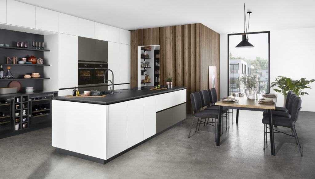 Cocina abierta al comedor con despensa recubierta de madera natural.