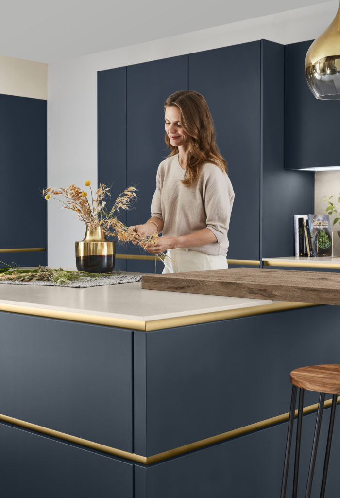 Mujer arreglando las flores en la cocina azul marina con tirador en gola dorado