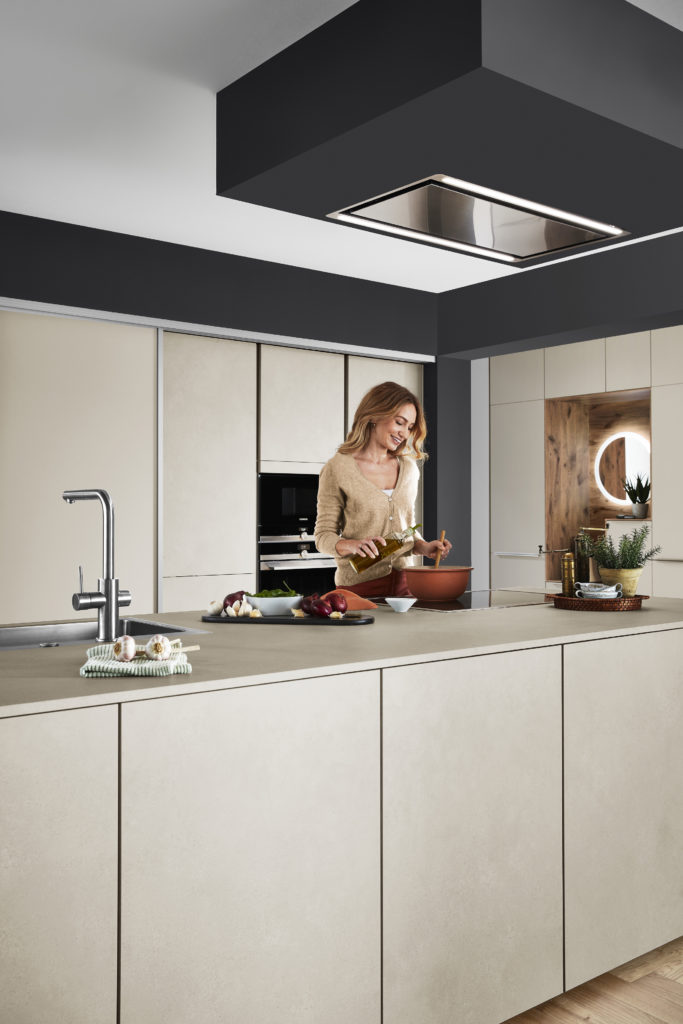 Mujer cocinando en cocina con isla de tono tierra y paredes en negro.