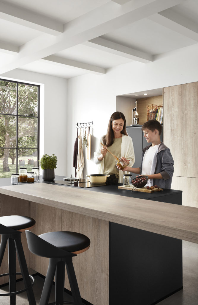 Madre e hijo cocinando juntos en preciosa cocina abierta con vistas al jardín.
